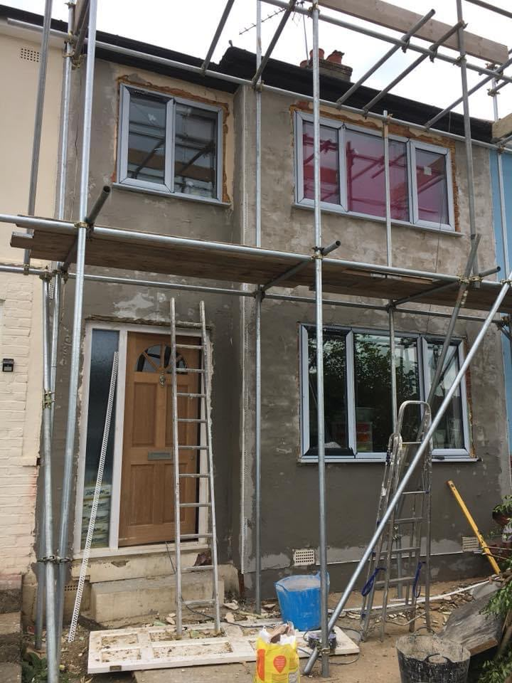 House under scaffolding with fresh grey render applied