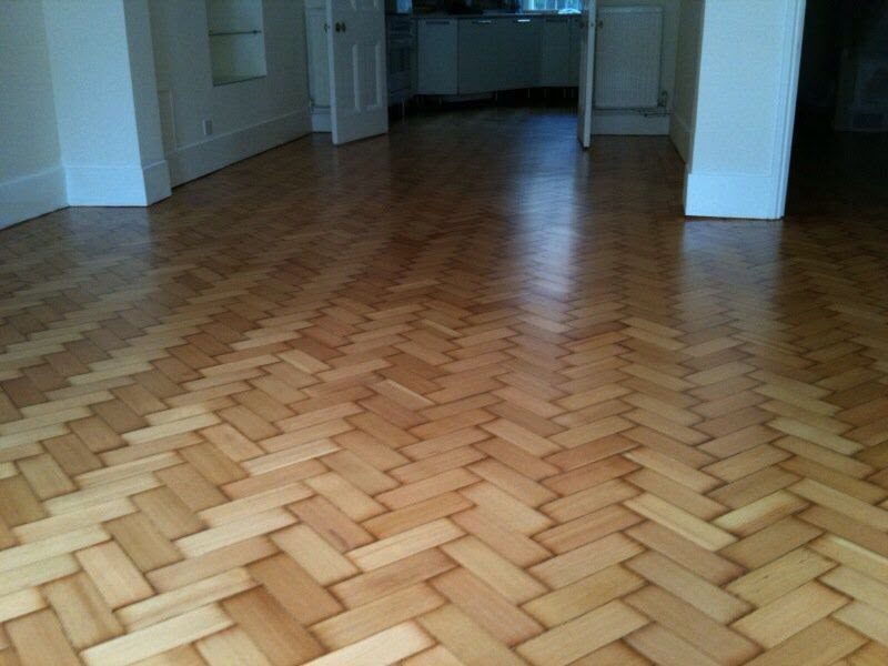 Restored herringbone parquet wood flooring in an open-plan room