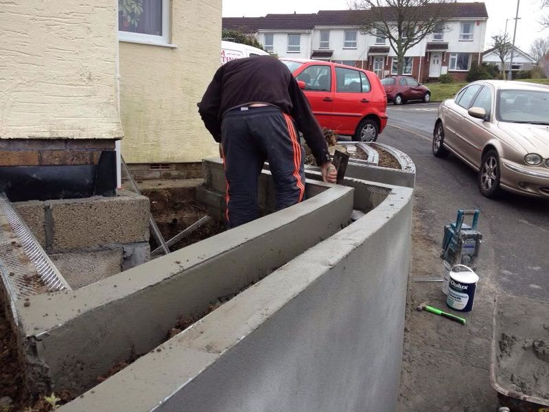 Tradesperson rendering a curved front garden retaining wall
