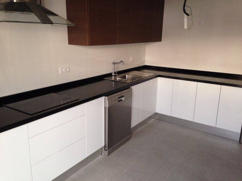 L-shaped kitchen with gloss white units, dark wood wall cabinets and black worktop by Aaron Steven Construction